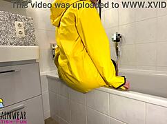Girl in yellow rubber raincoat teases with a rubber duck in the bathroom