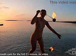Pretty european girl performs nude fire dancing on usa beach at sunset
